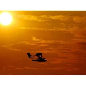 A Pilot Flies a Small Plane Past the Setting Sun Over Lake 
